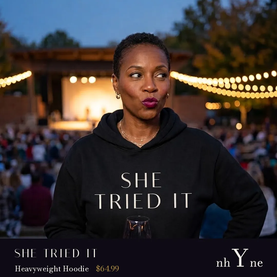 A woman at an outdoor concert in a black SHE TRIED IT hoodie