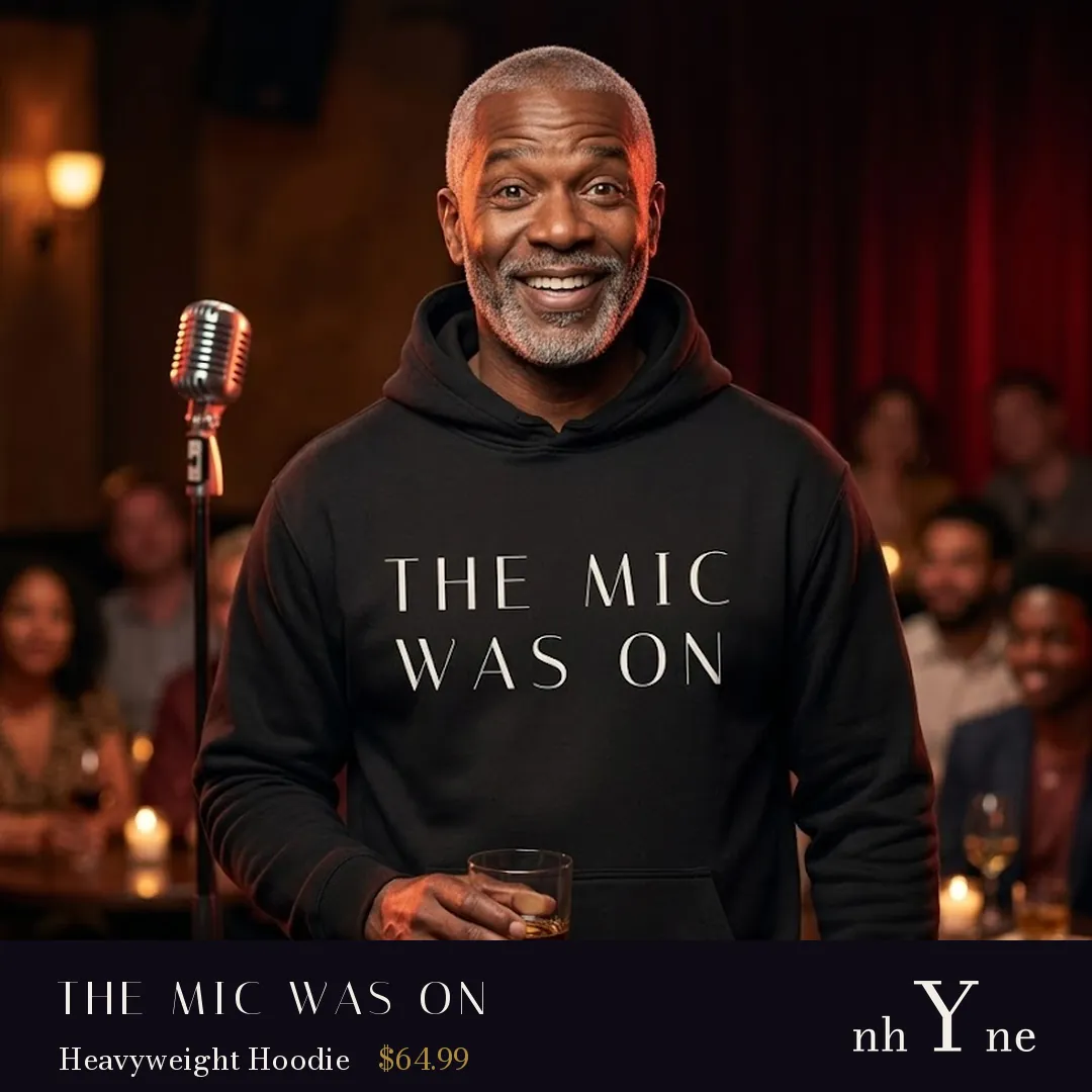 A smiling man at a lounge in a black THE MIC WAS ON hoodie