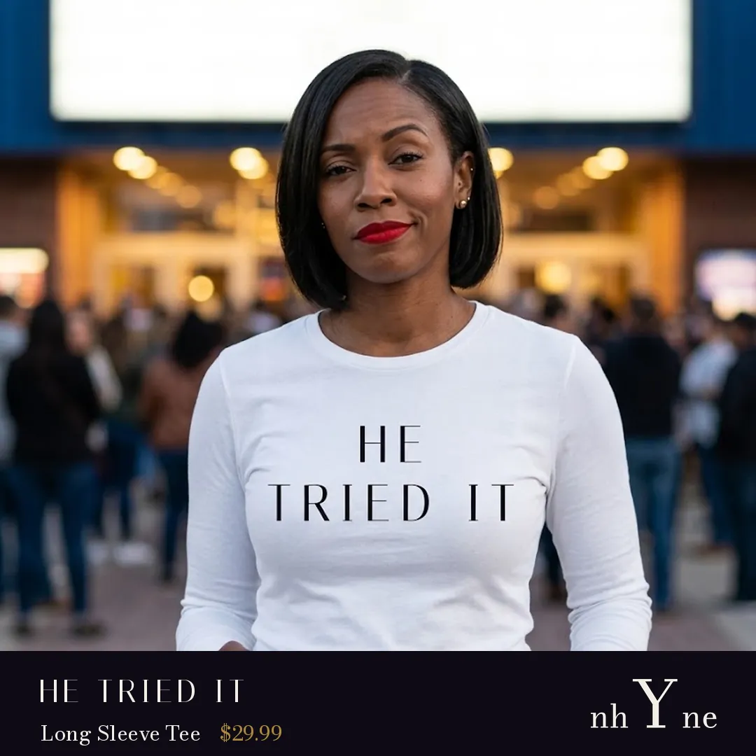 A woman outside a theatre in a white HE TRIED IT long sleeve tee